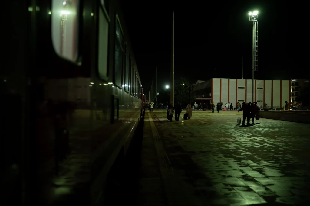 Passengers on a railway platform at night beside a waiting train