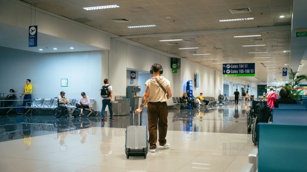 Traveller walking through an airport terminal with a wheeled suitcase
