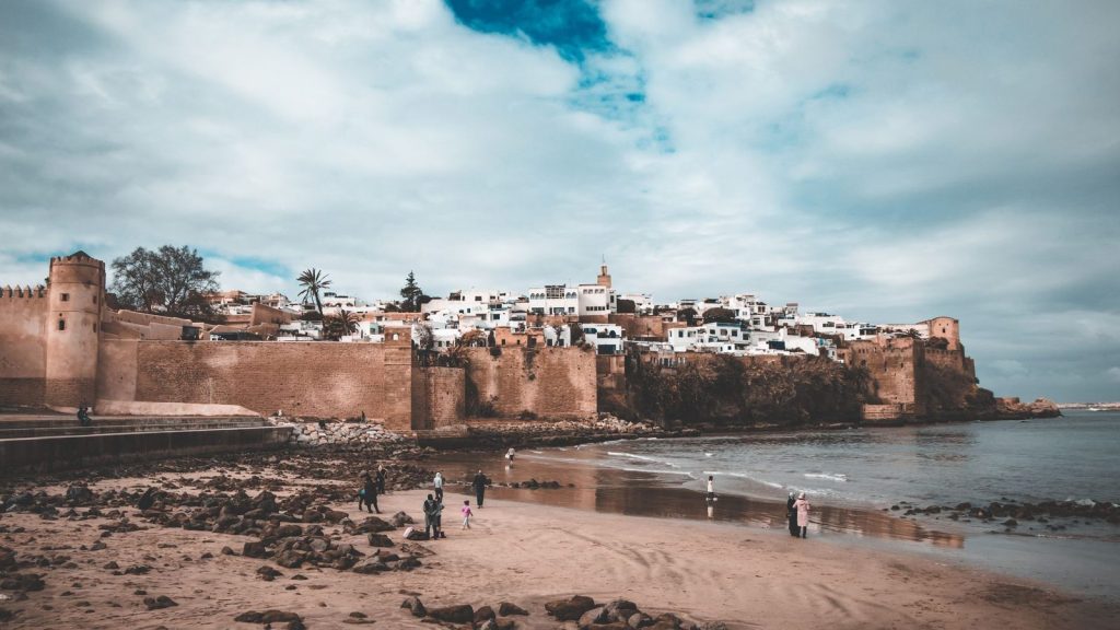 A scenic view of an ancient fortified city with sandy beach and blue skies.