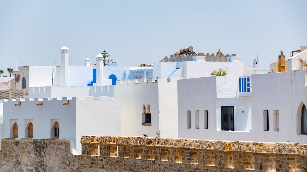 Charming view of traditional white and blue buildings under clear skies in Asilah, Morocco.