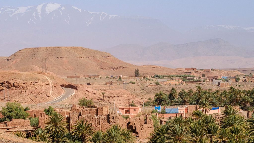 Picturesque view of Moroccan landscape with Atlas Mountains and palm trees.