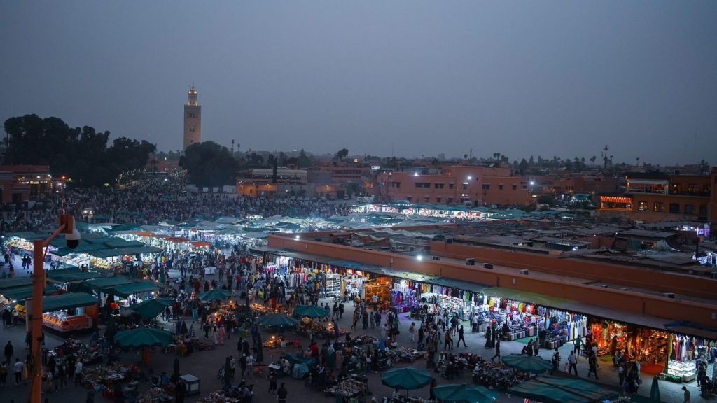 Jemaa el-Fna square in Marrakech at dusk, with the market lights and the Koutoubia minaret behind