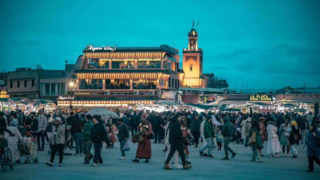 Crowd gathered at iconic Jemaa el-Fnaa square in Marrakesh during dusk, vibrant and lively atmosphere.