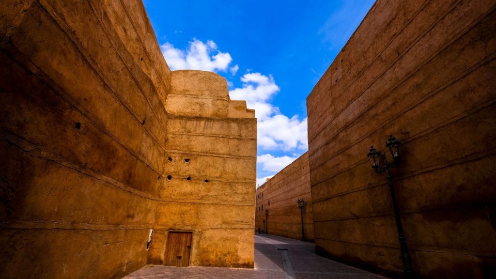 Discover the historic architecture of Marrakech with high walls under a vibrant blue sky.
