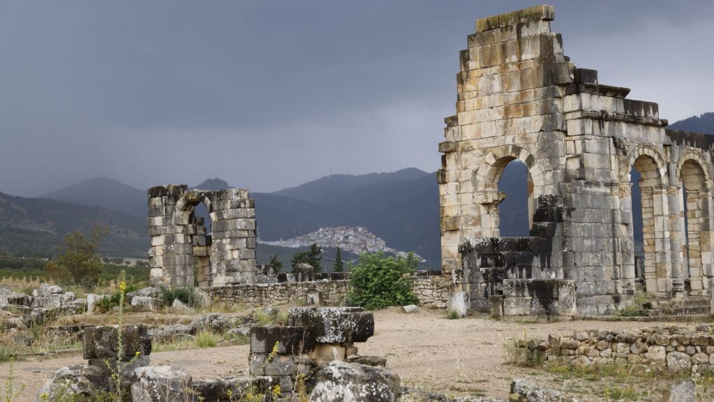 Explore the ancient Roman ruins of Volubilis, Morocco, amidst a dramatic landscape.