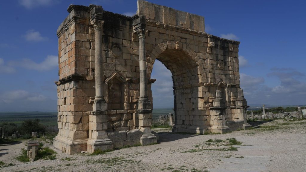 Captured at the ancient site of Volubilis, this arch stands under a clear blue sky, showcasing Roman architectural prowess.