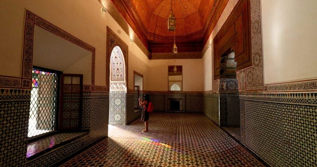 Une salle carrelée du palais de la Bahia à Marrakech, avec un plafond de cèdre peint et la lumière colorée des fenêtres