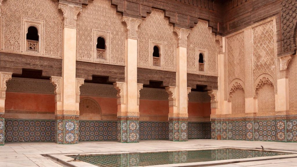 The courtyard of the Ben Youssef Madrasa in the Marrakech medina, with carved walls, zellige tiles and a pool