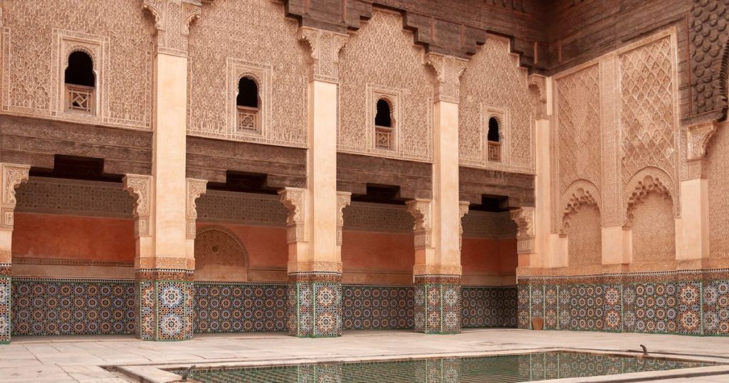 The carved courtyard of the Ben Youssef Madrasa in Marrakech with its tiled walls and basin