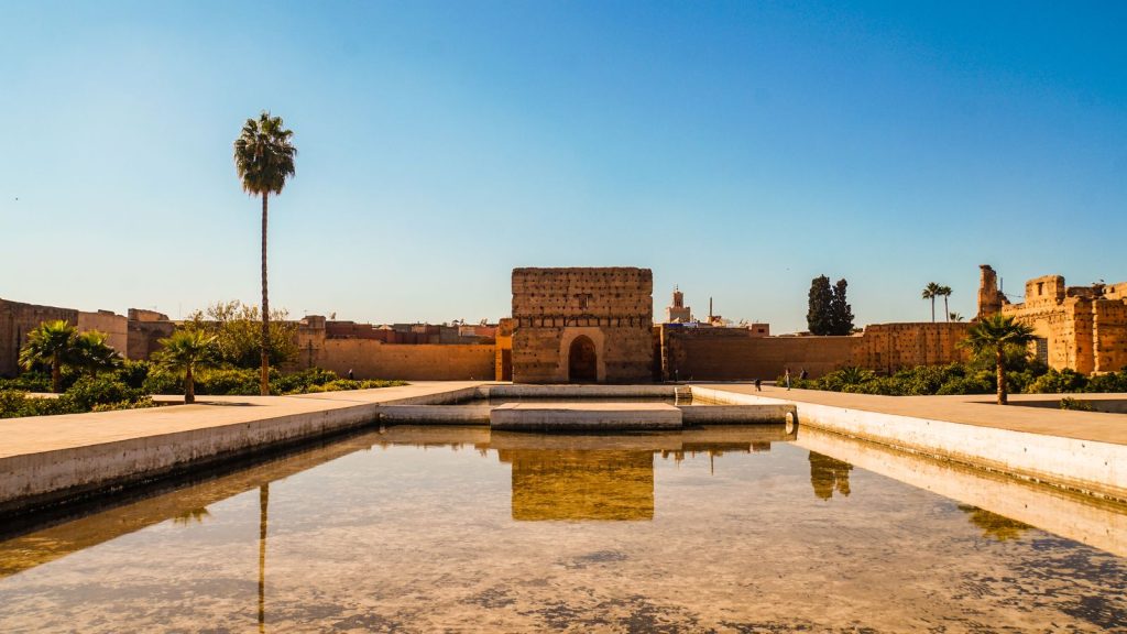 The El Badi Palace in Marrakech reflected in its long basin under a clear blue sky