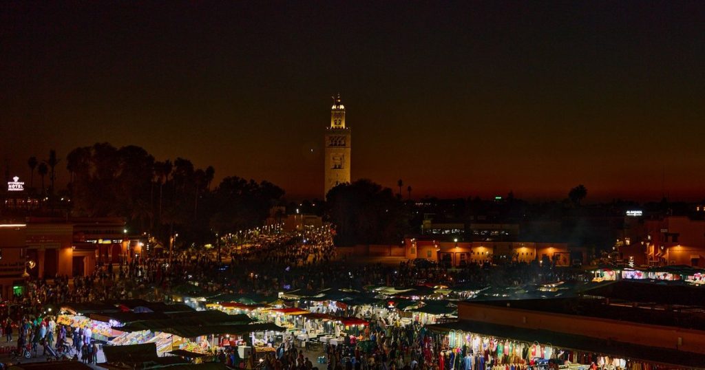 Jemaa el-Fna square in Marrakech at night with the market stalls lit and the Koutoubia minaret behind